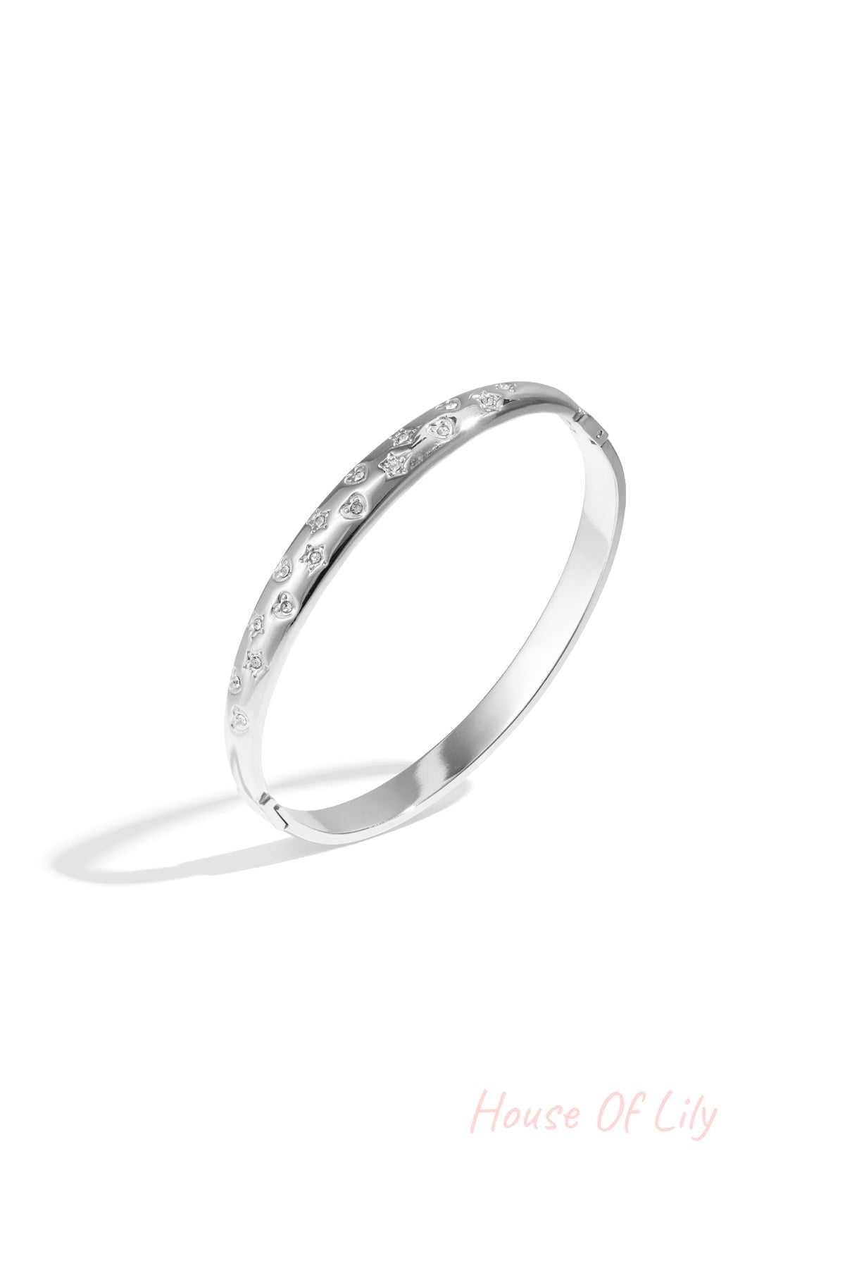 Silver-tone bangle bracelet with star and heart-shaped crystal accents on white background