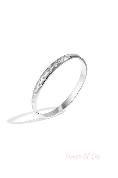 Silver-tone bangle bracelet with star and heart-shaped crystal accents on white background