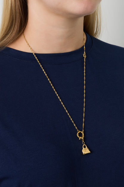 Model wearing gold chain necklace with a small handbag charm over navy top