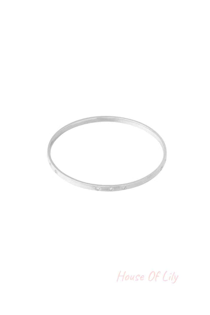 Slim silver bangle with small rhinestone accents photographed on a white background