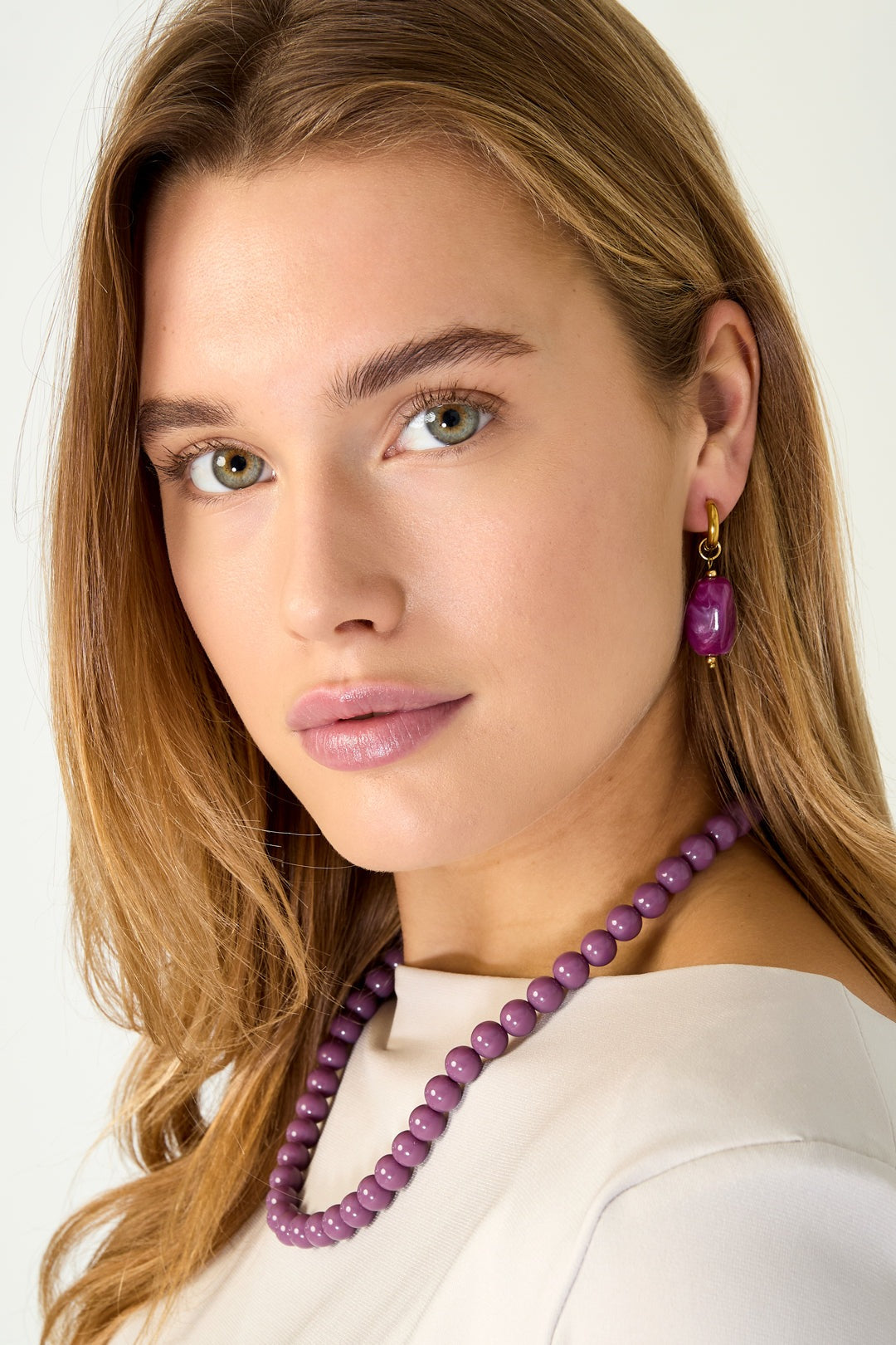 Model wearing deep pink resin drop earrings paired with matching deep pink bead necklace