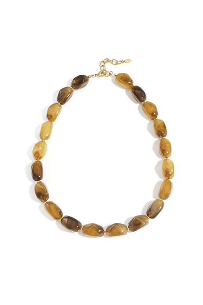 Close-up of chocolate and amber-toned chunky beaded necklace on woman wearing maroon top