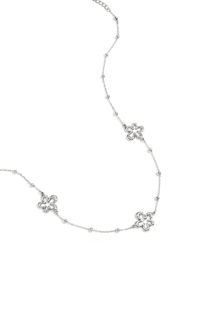 Close-up of silver necklace variant featuring the same hollow flower charms and bead accents on white background