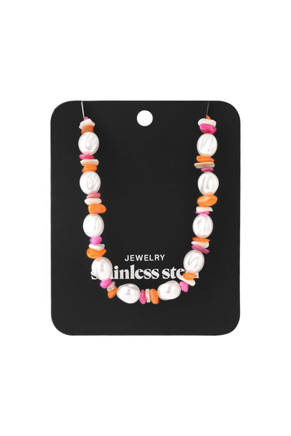 Necklace featuring white baroque pearls interspersed with small, colorful pink and orange chip beads on a display card.