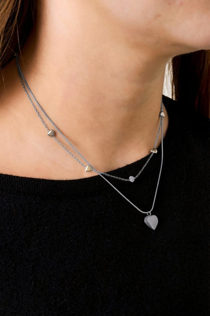 Delicate silver-tone layered necklace featuring a snake chain and a dainty link chain with small, minimalist heart charms.