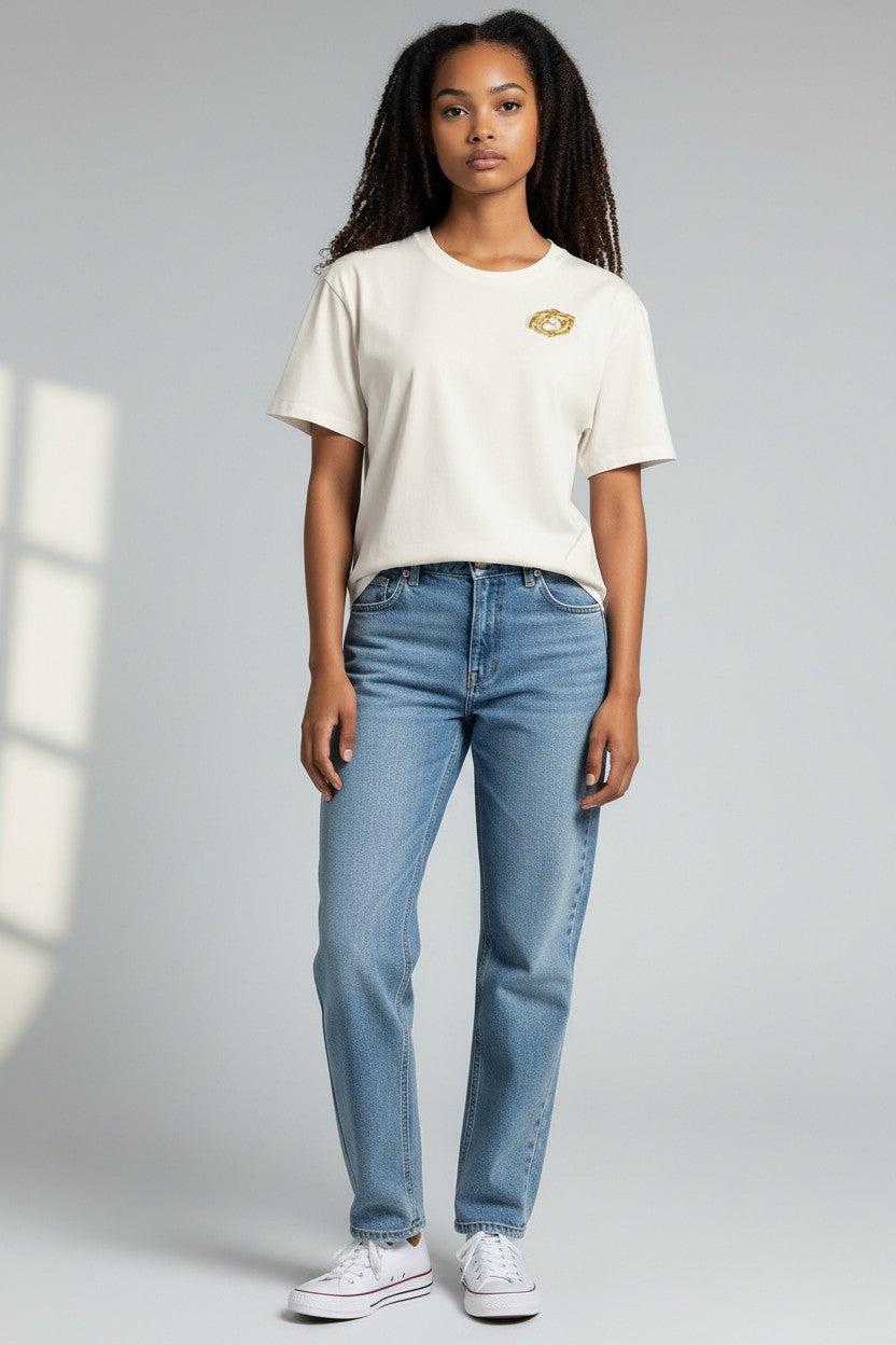 Model wearing a white t-shirt with a Golden Spiral Brooch, an intricate, round gold-toned abstract accessory.