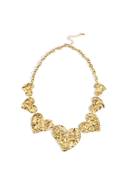 Chunky hammered heart necklace in gold metal with large linked hearts and adjustable chain on white background