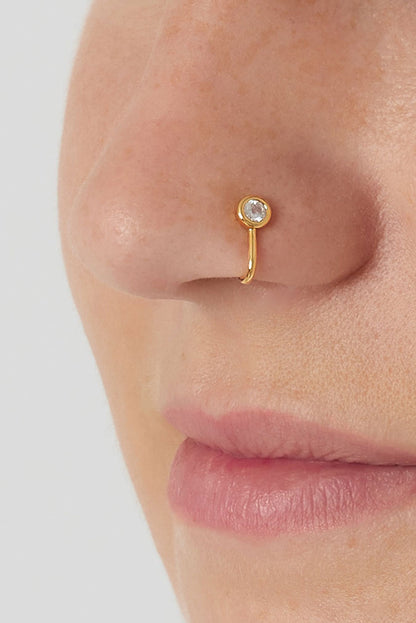Close-up of a gold zircon nose cuff worn on a woman's nose, showing minimalist and soft design