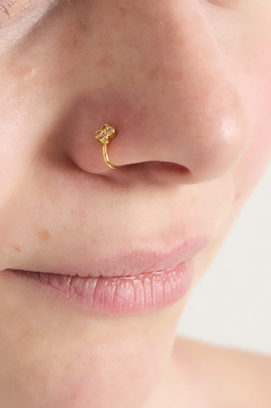 Close-up of a woman wearing the gold zircon clover and heart nose cuff on her nostril