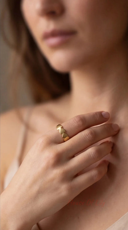 Close-up of a person wearing a gold ring on their finger, with a soft focus on the background.