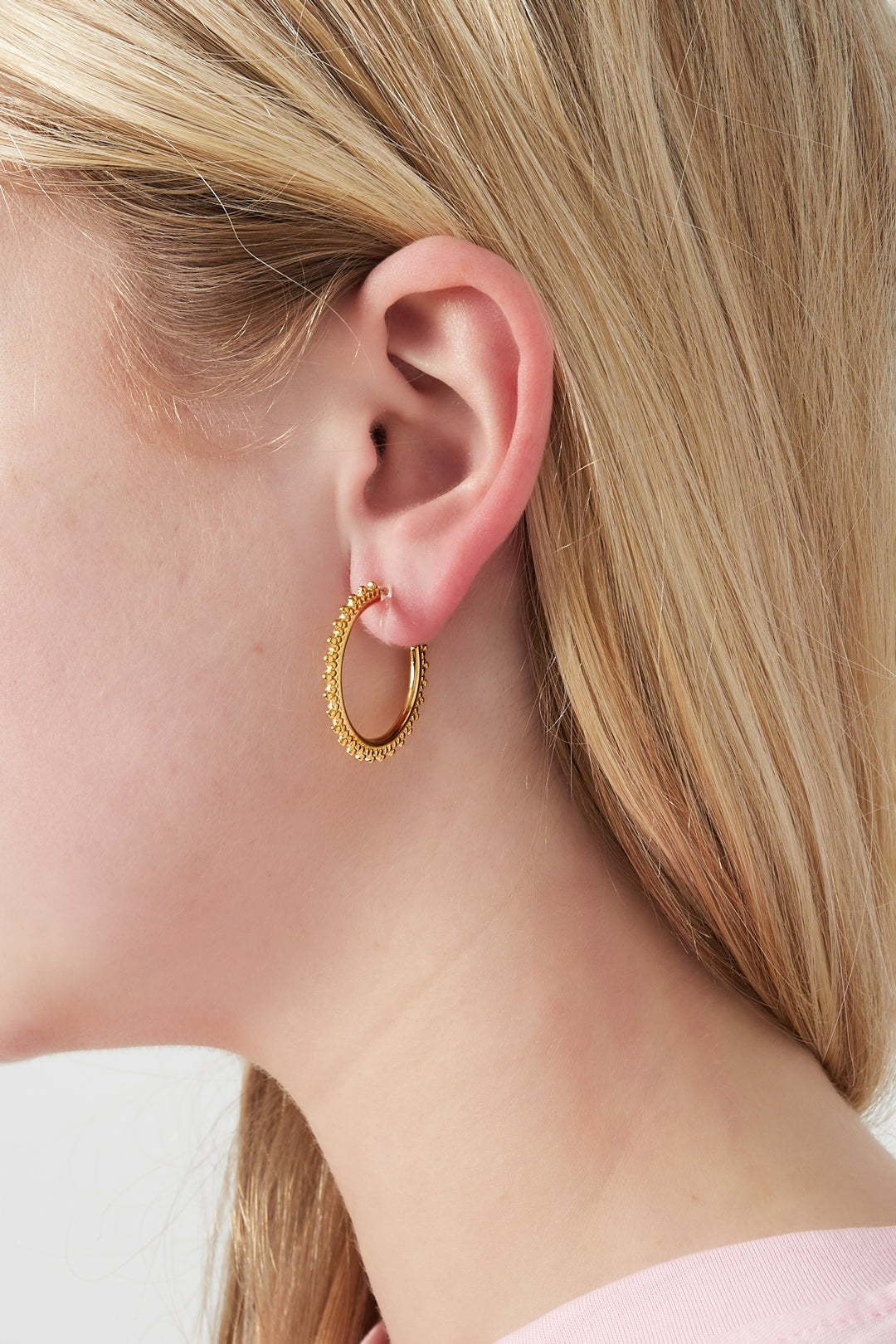 Close-up side profile of woman wearing gold beaded edge clip-on hoop earring