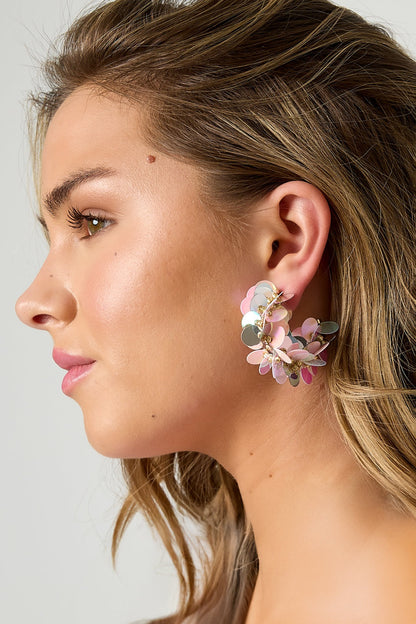 Close-up side view of pink and silver iridescent sequin hoop earring on model's ear