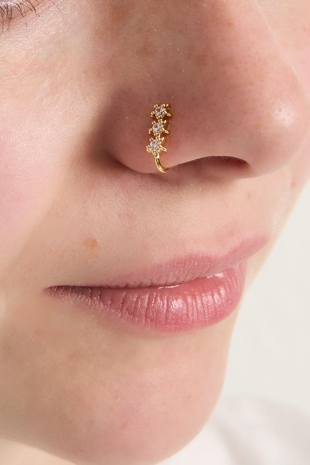 Model wearing gold starry nose cuff featuring four zircon stones, showcasing minimalist and soft jewelry style