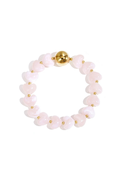 Peach light pink heart-shaped acrylic beaded bracelet with gold bead accent on white background