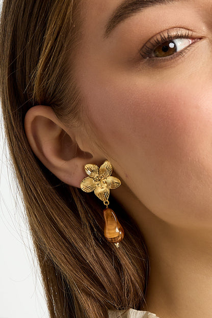 Pair of gold-tone flower drop earrings with baby pink organic acrylic bead on white background