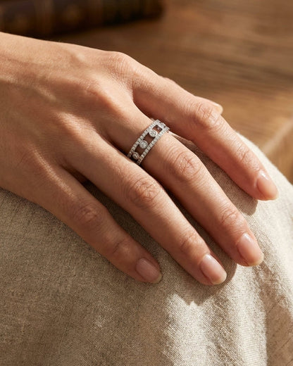 Silver band ring with pavé-set stones and three floating circular gems worn on a finger.