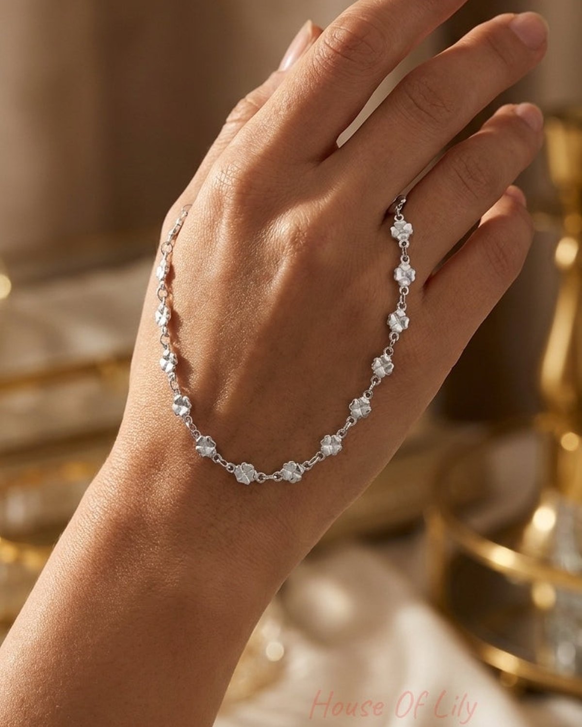 Dainty silver lucky clover chain bracelet wrapped loosely around a hand.