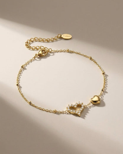 Gold-finish chain bracelet featuring a crystal-set open heart and a solid gold heart charm.