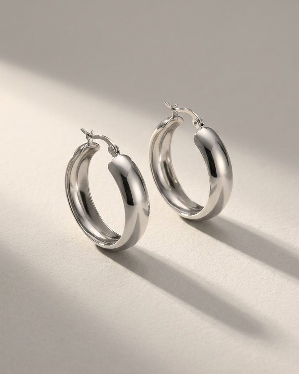 House of Lily silver-tone thick hoop earrings with a polished, minimalist finish on a neutral background.