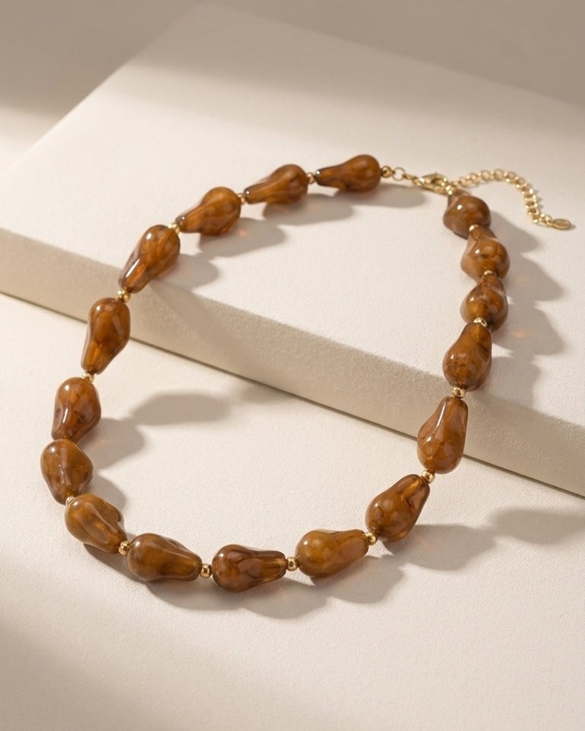 Chunky marbled amber-brown resin beaded necklace with gold-tone metal spacers and chain.