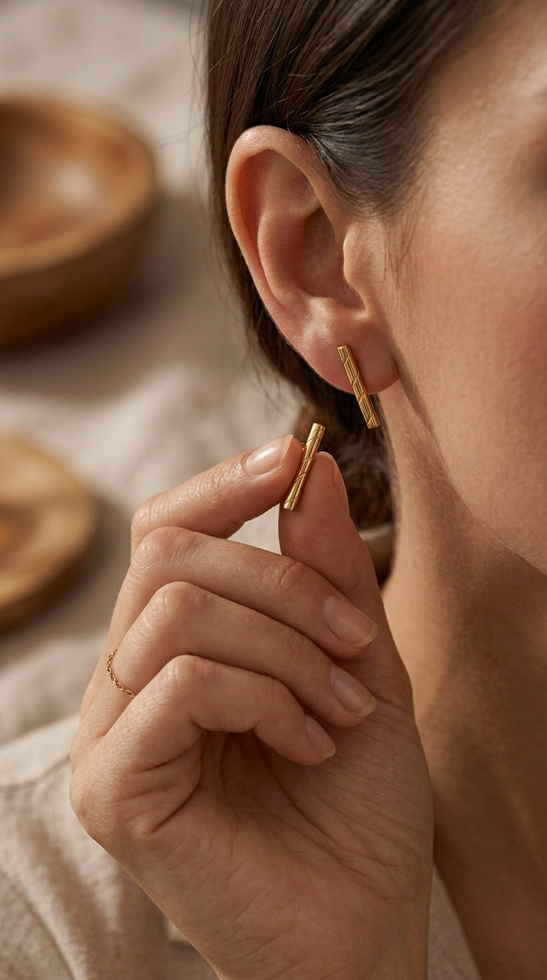 Gold bar stud earrings featuring a delicate diagonal etched texture, styled as a minimalist pair.