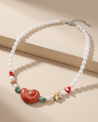 Beaded seashell necklace with white pearls, a red conch shell, and a beige starfish charm.