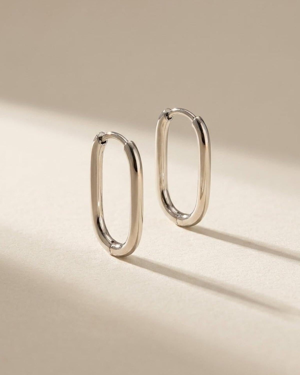 Minimalist polished silver oval hoop earrings by House of Lily on a neutral background.