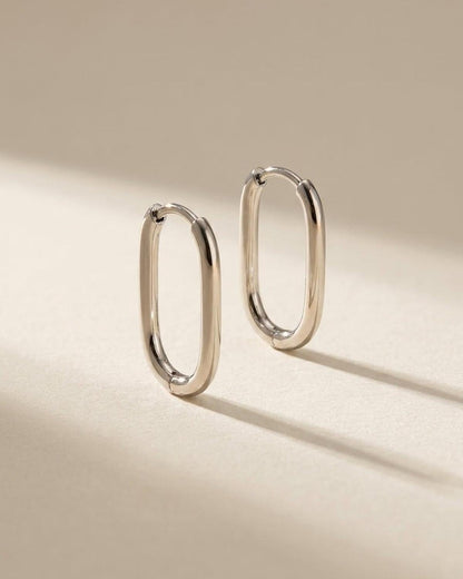 Minimalist polished silver oval hoop earrings by House of Lily on a neutral background.