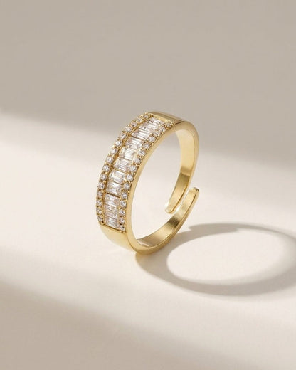 Gold open ring with a center row of baguette stones bordered by small round crystals.