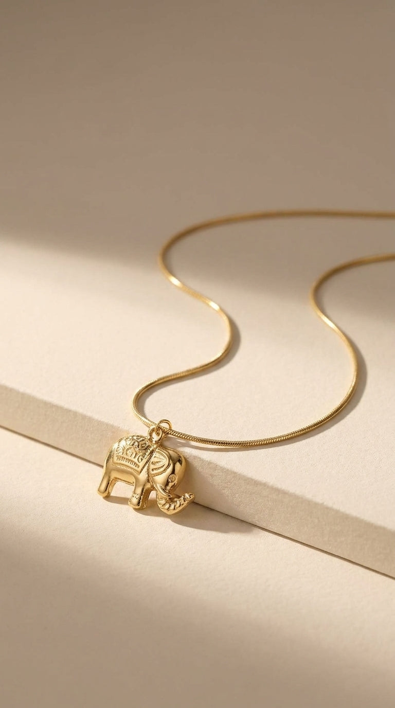 Polished gold elephant pendant necklace with an engraved pattern, on a thin gold chain.