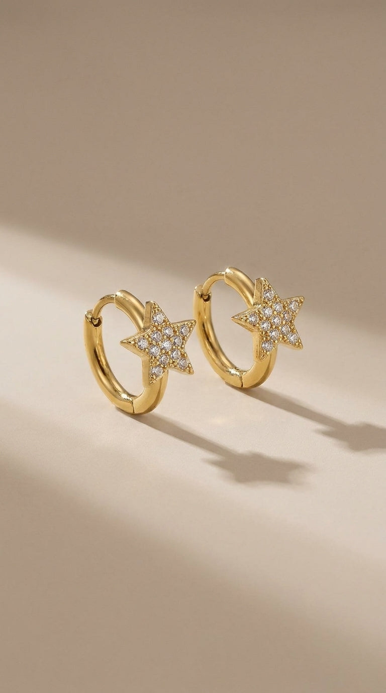 Gold-finish huggie hoop earrings featuring pavé-set crystal star charms.