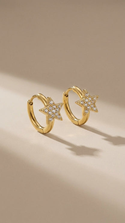Gold-finish huggie hoop earrings featuring pavé-set crystal star charms.
