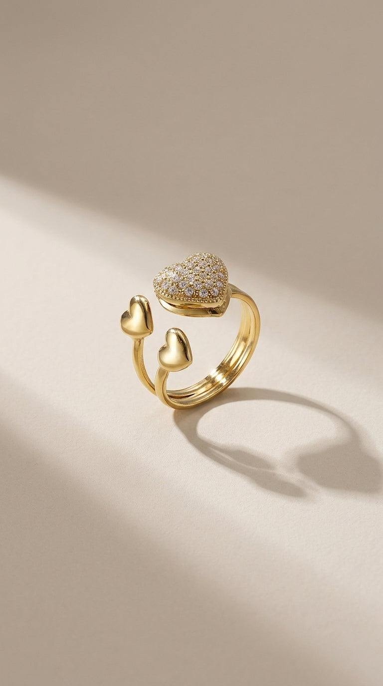 Gold-finish steel ring featuring a large, pavé-set crystal heart and two smaller polished heart accents.