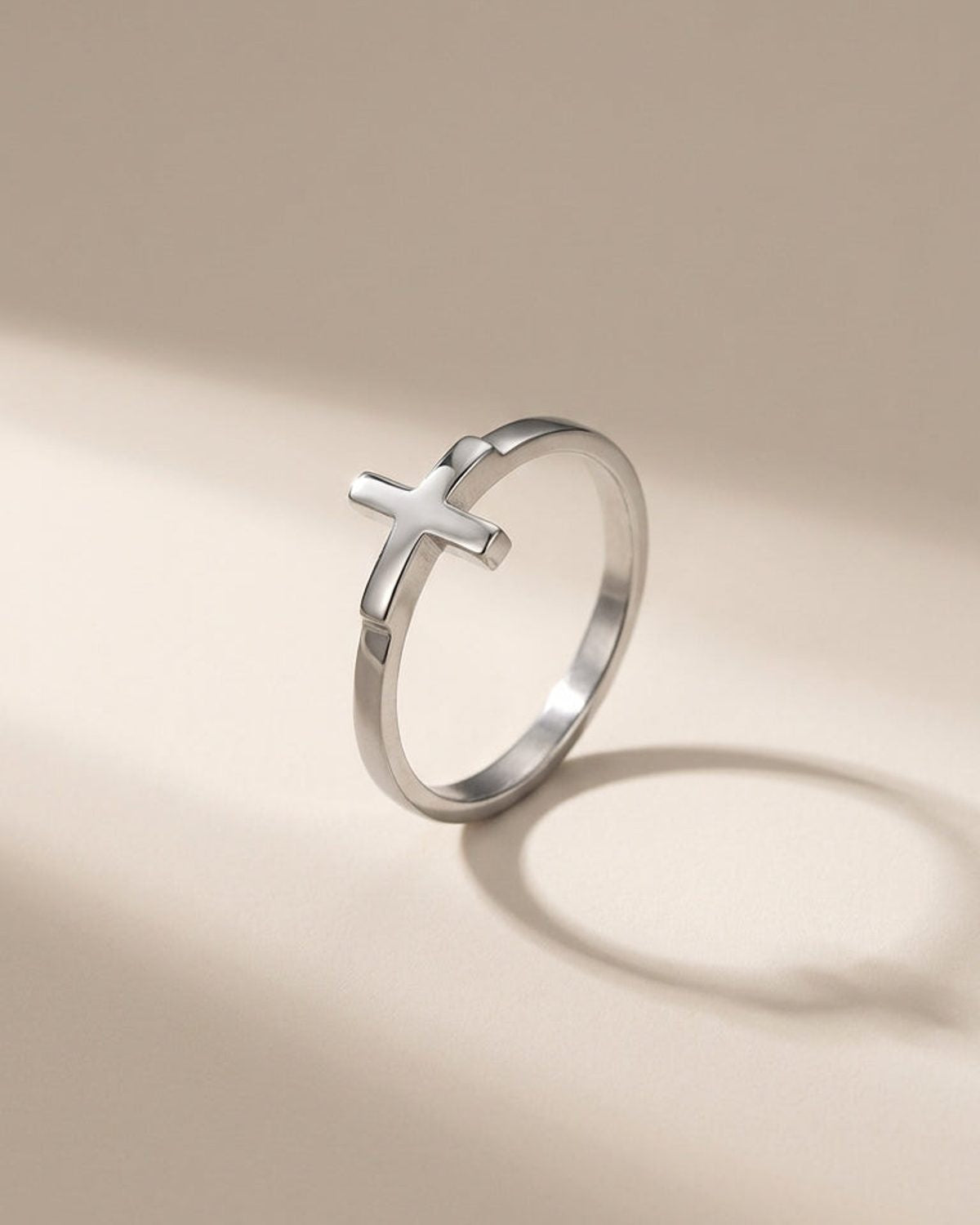 Minimalist silver metal ring featuring a small cross shape on the band.