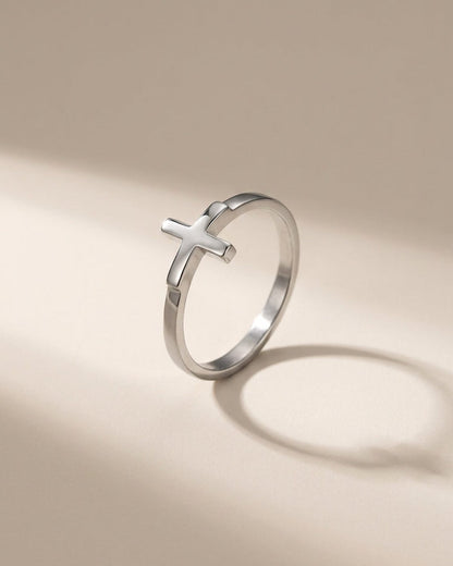 Minimalist silver metal ring featuring a small cross shape on the band.