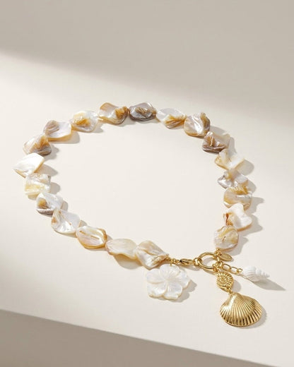 A short necklace of iridescent white mother-of-pearl nuggets with a gold clasp and seashell charms.