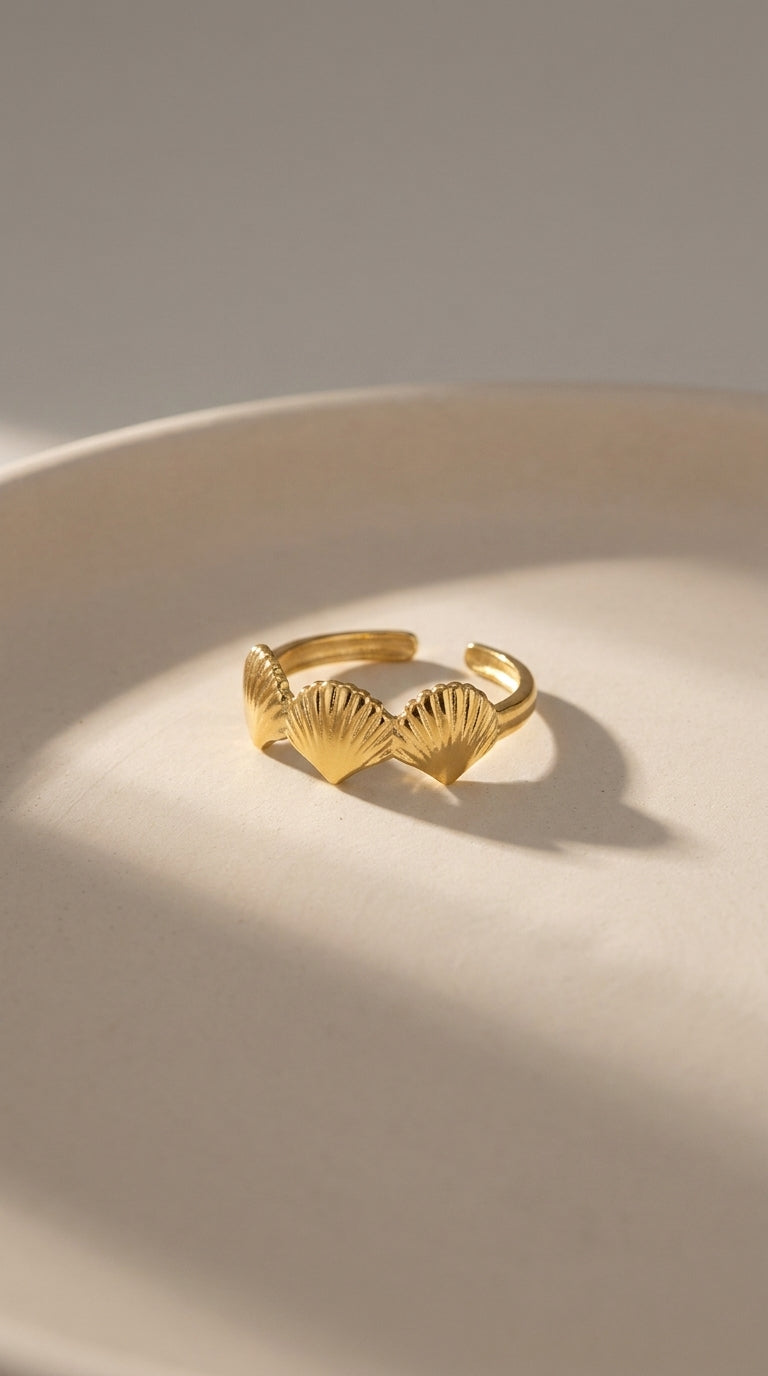 Minimalist gold ring featuring three delicate, fan-shaped shell charms in a coastal, polished metallic design.