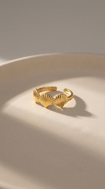 Minimalist gold ring featuring three delicate, fan-shaped shell charms in a coastal, polished metallic design.