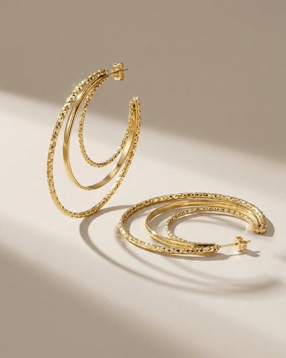 Stacked Aura Gold earrings: triple-hoop gold earrings with mixed textured and polished bands in a modern style.