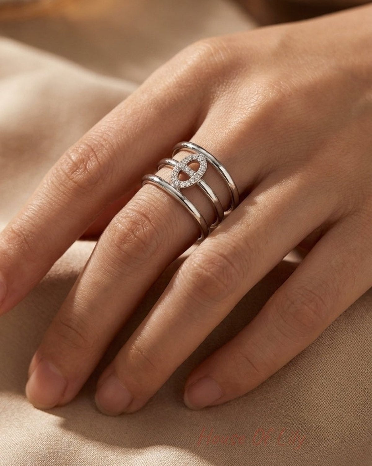 Silver elliptical tiered statement ring with pave stones on the center motif, worn on a hand.