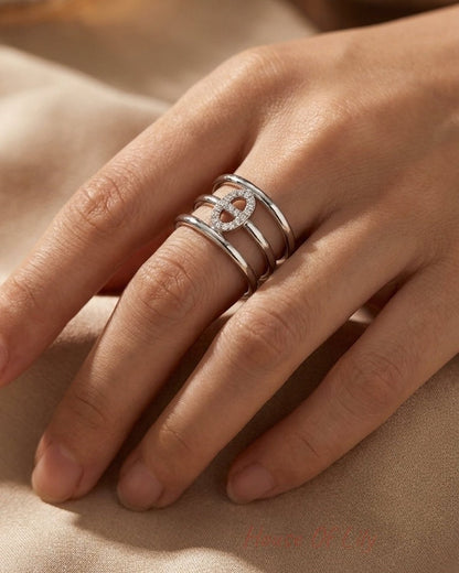 Silver elliptical tiered statement ring with pave stones on the center motif, worn on a hand.