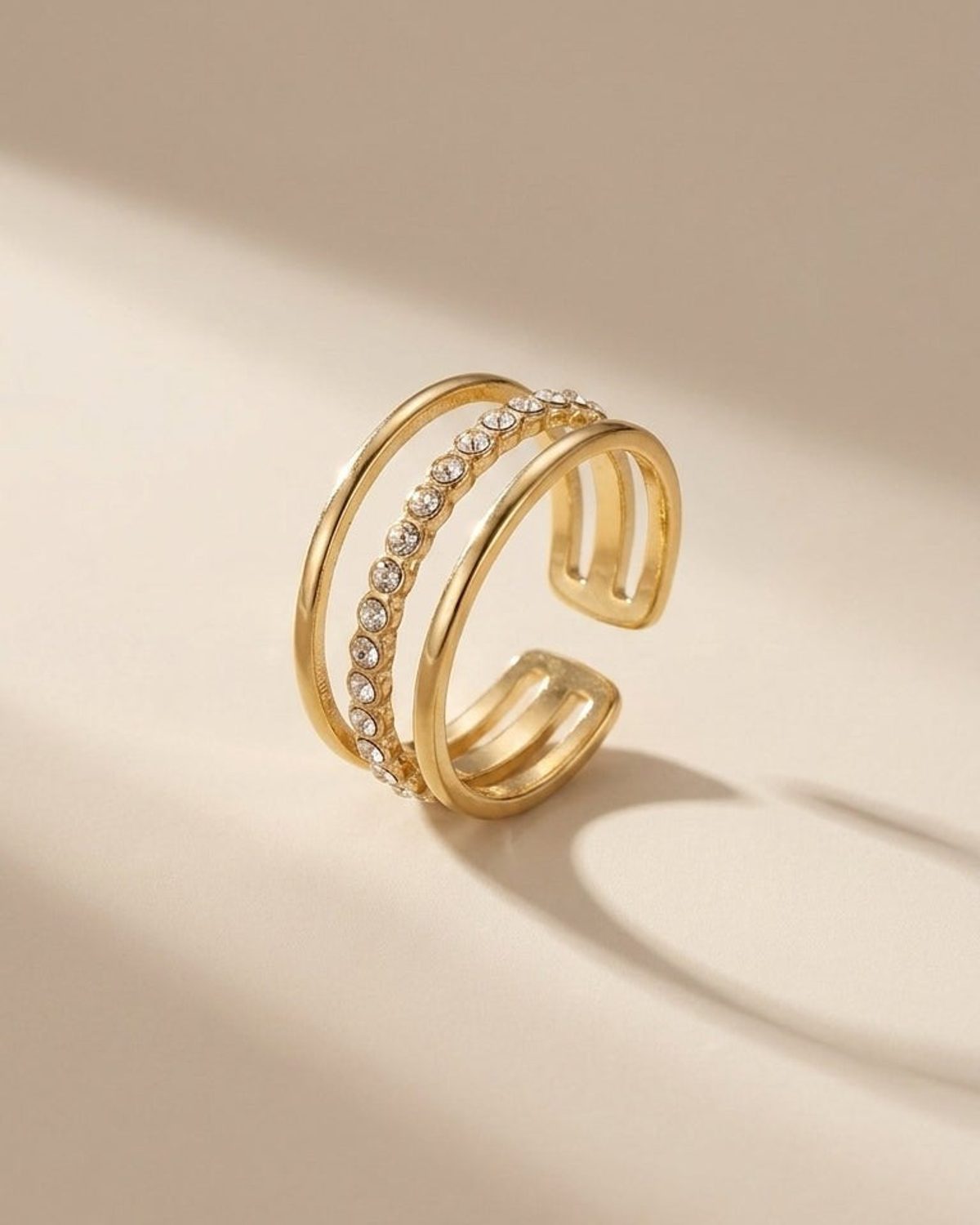 Triple layer gold ring featuring a central band paved with small clear stones between two smooth gold bands.