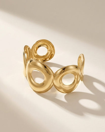Gold Geometric Cuff featuring linked, smooth gold circles with beaded edges on a neutral background.