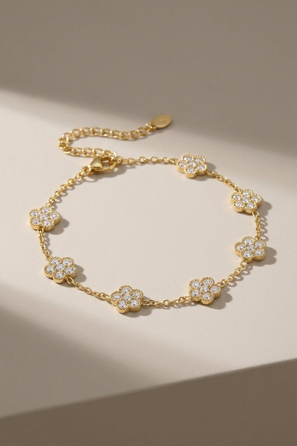 Gold flower charm bracelet featuring crystal-pave flower stations along a delicate link chain.