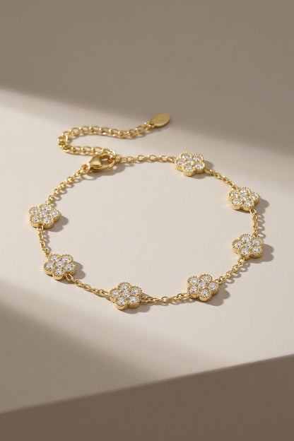 Gold flower charm bracelet featuring crystal-pave flower stations along a delicate link chain.