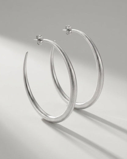 Aura Melt Gold hoop earrings in silver, featuring a sleek, minimalist style with a textured, matte finish.