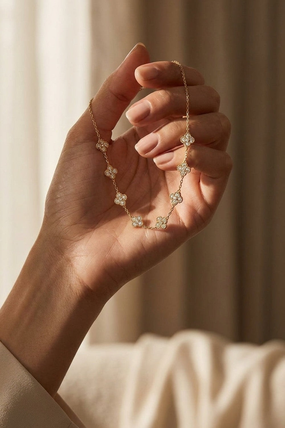 Gold-tone chain necklace featuring multiple paved zicron floral charms, displayed in an open hand.