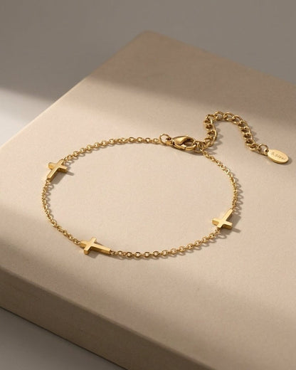 Delicate gold-colored metal chain bracelet with three small cross charms.