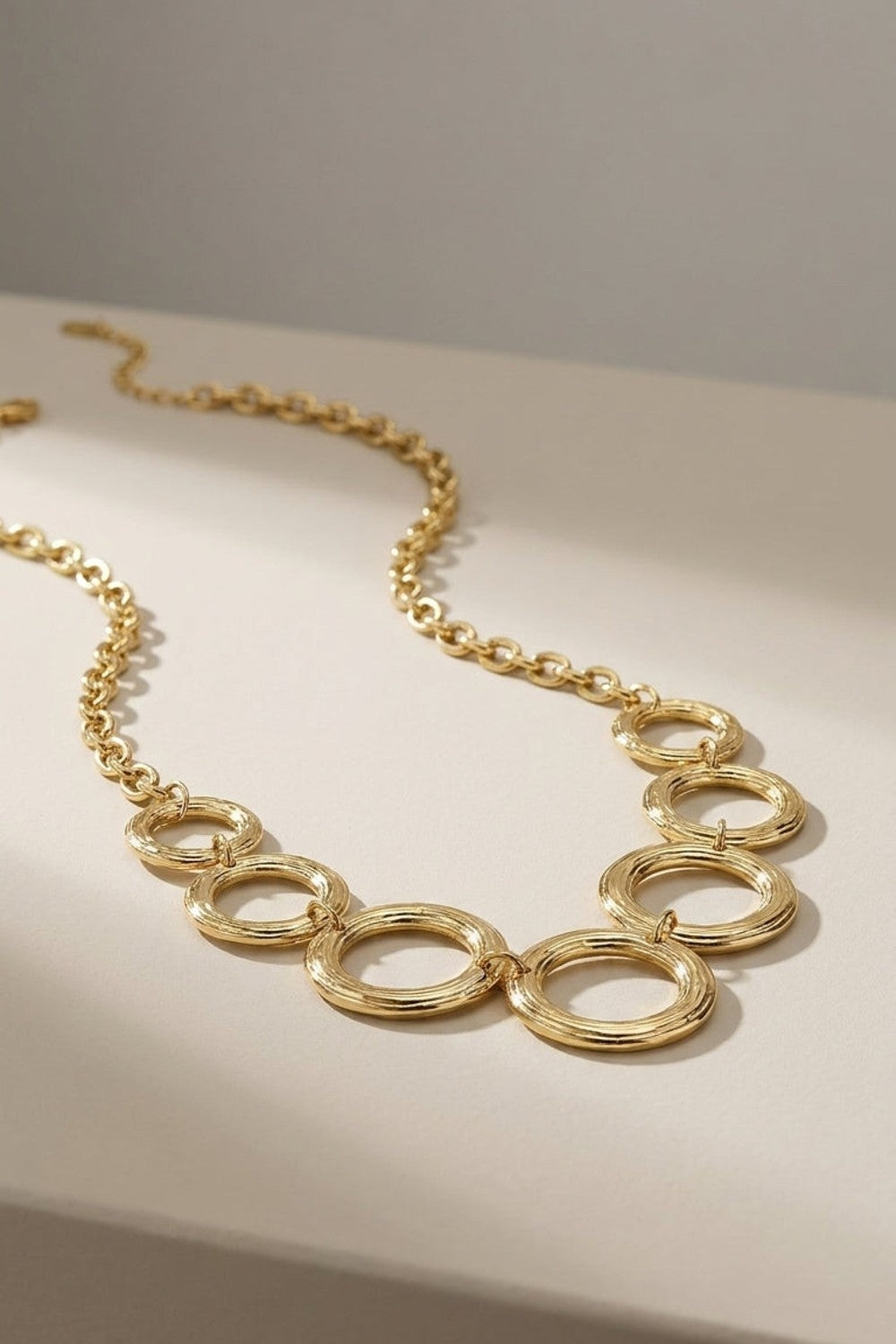 Gilded Chain Statement Necklace featuring interlocking gold rings on a textured link chain.