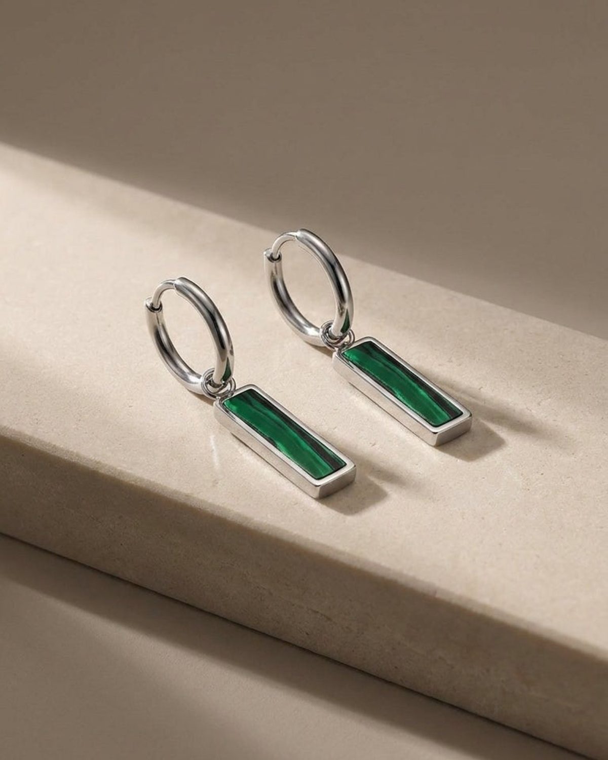 Silver hoop earrings with rectangular green stone drop bars.